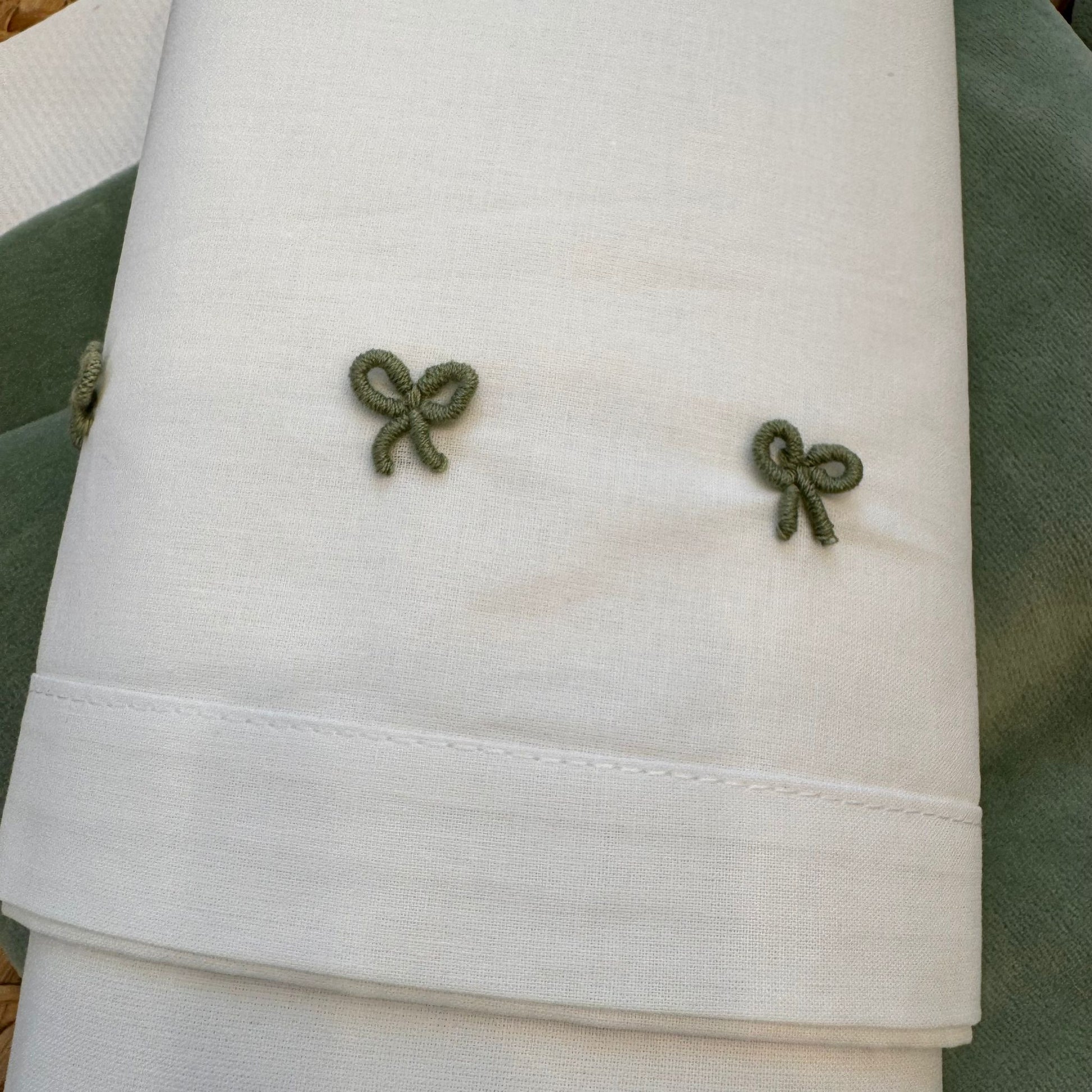 Lenzuolini bianchi con ricami verde salvia coordinati