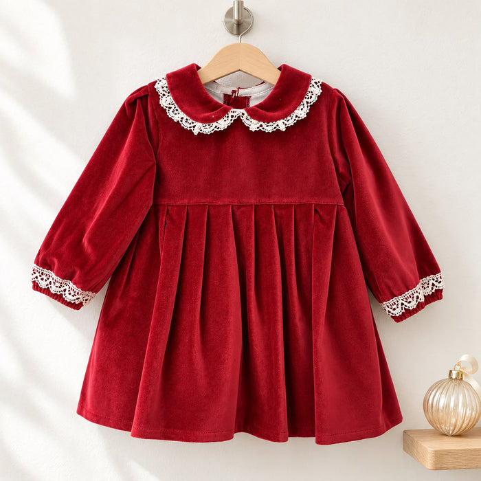 Abito bimba in velluto rosso 100% cotone con colletto Peter Pan rifinito in pizzo bianco, maniche lunghe con polsini in pizzo e gonna ampia a pieghe.