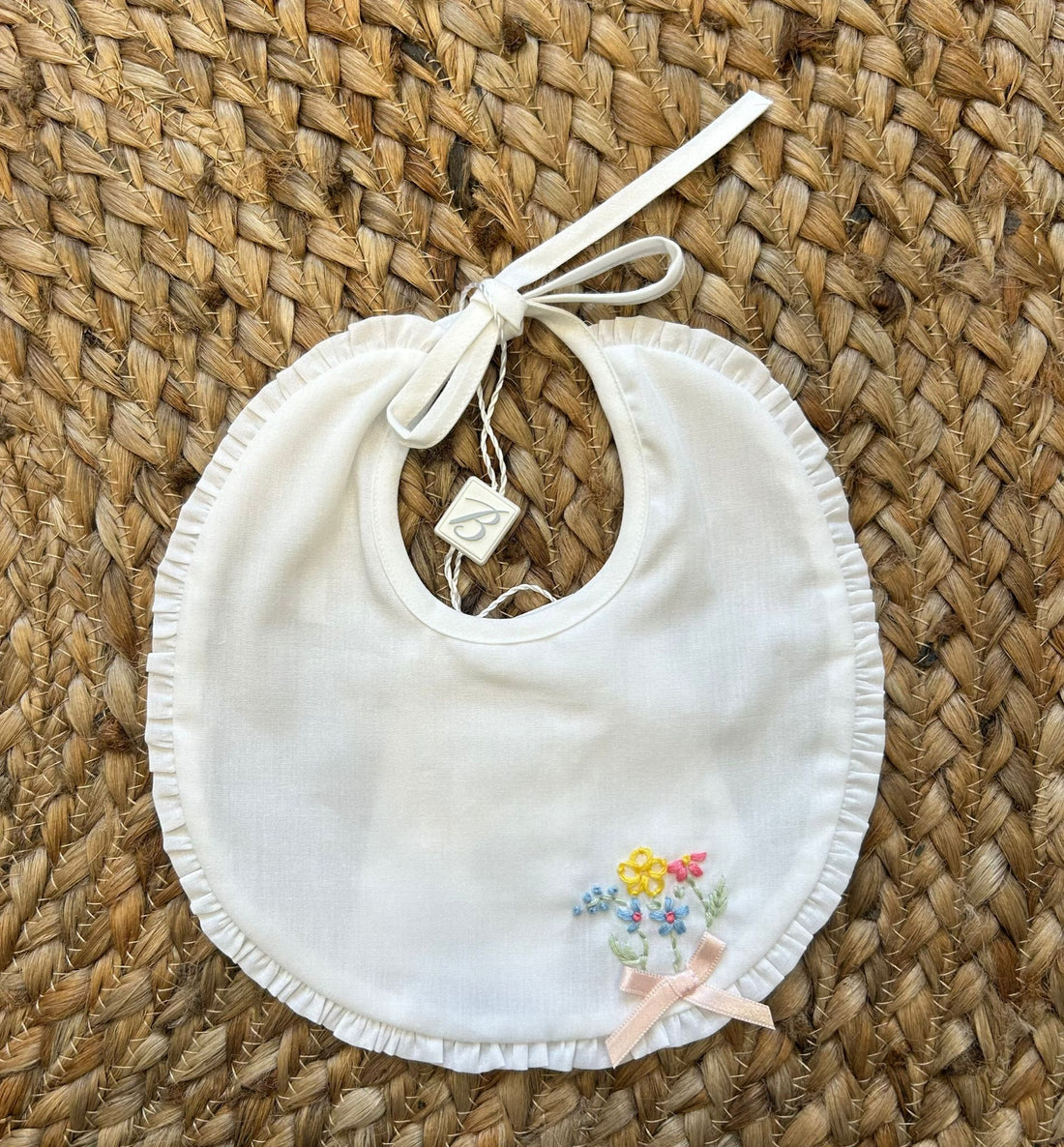 Bavaglino bianco con ricami floreali e fiocco rosa cipria