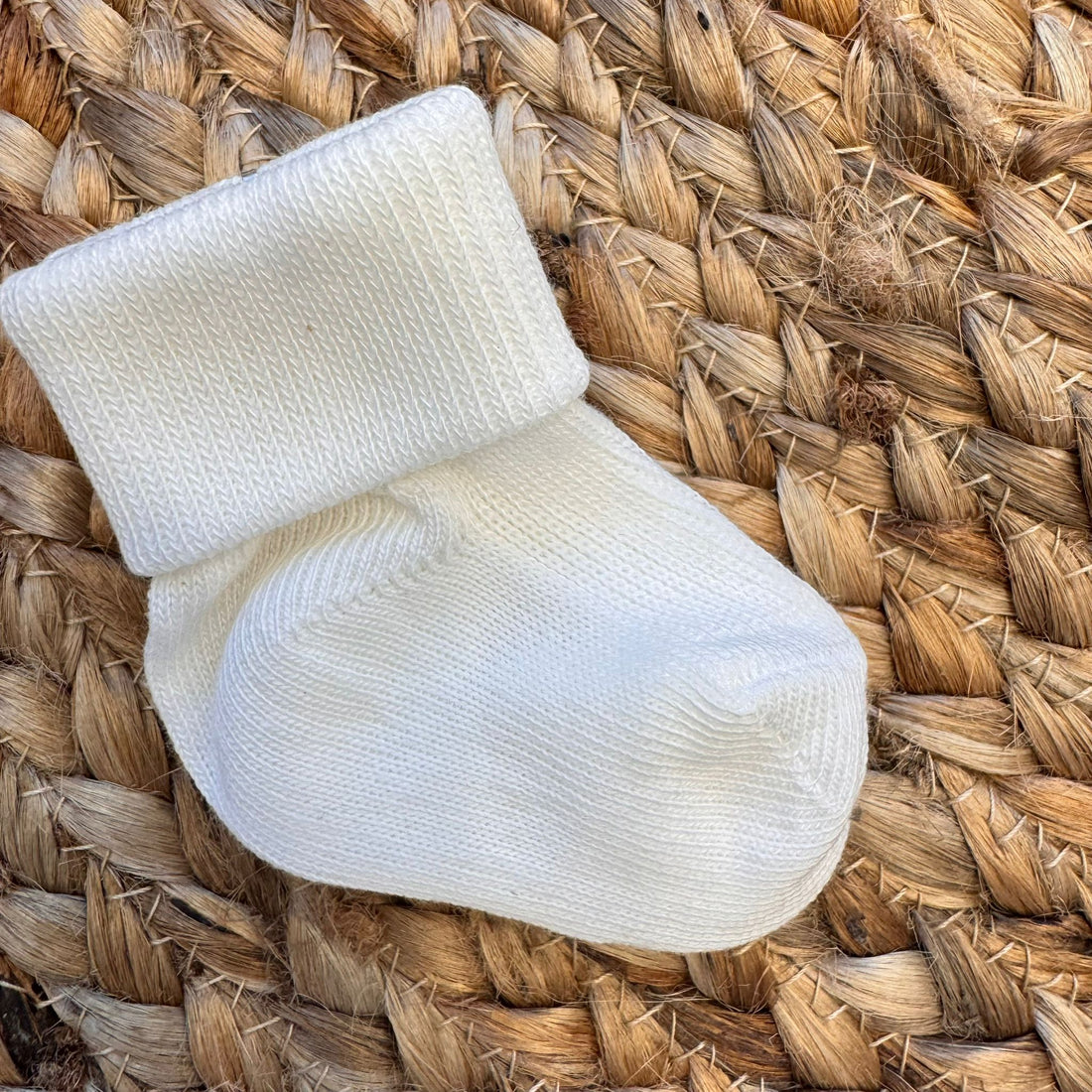 Calzina unisex bianco latte in caldo cotone, perfetta per corredino o baby shower.