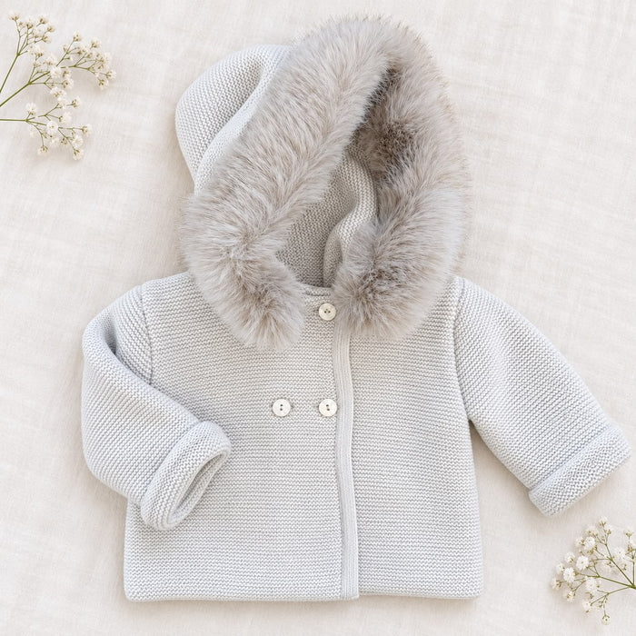Cappottino battesimo bimbo beige chiaro in maglia con ampio cappuccio bordato effetto pelliccia, bottoni chiari e maniche lunghe.