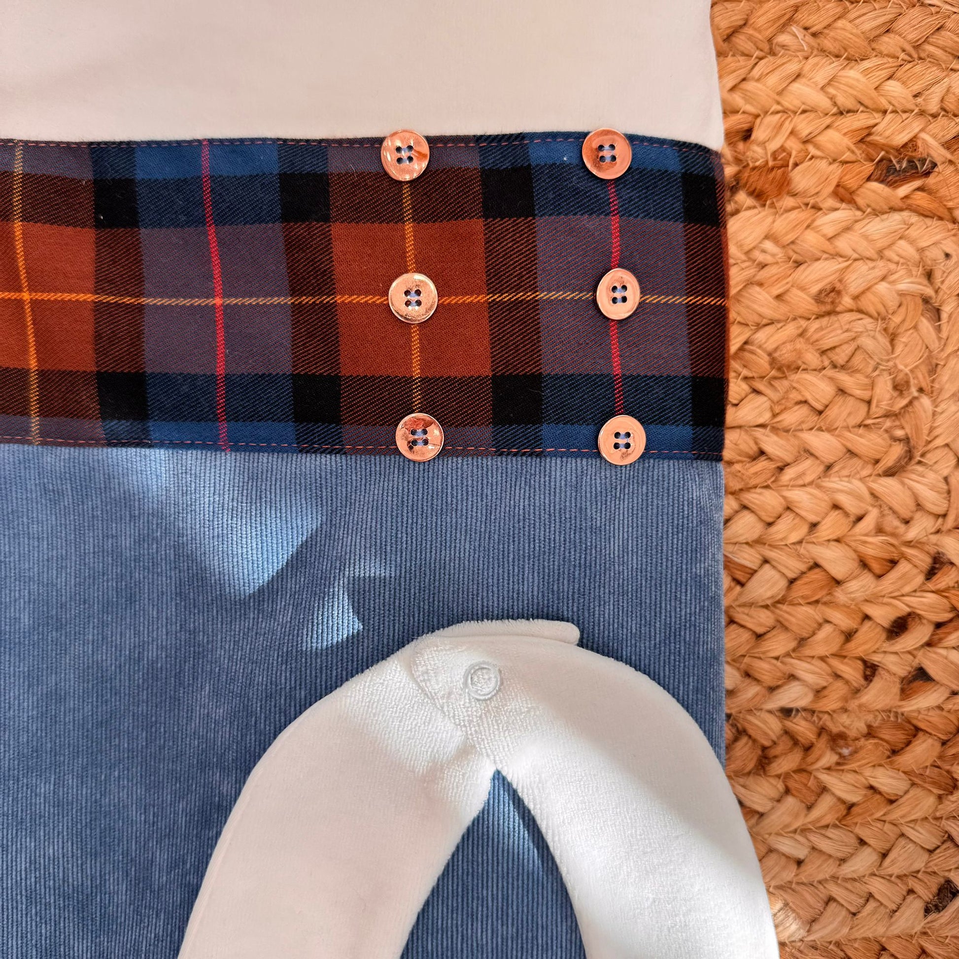 Dettaglio copertina con fascia tartan e bottoni su base in vellutino azzurro