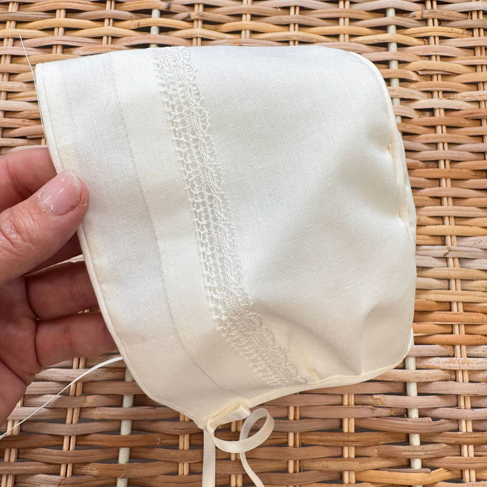 Cuffietta battesimale unisex bianca con ricamo decorativo e laccetti in raso.