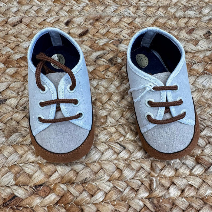 Scarpe culla in tessuto bicolore beige e bianco con punta rinforzata in suede marrone e chiusura a lacci. Perfette per neonati.