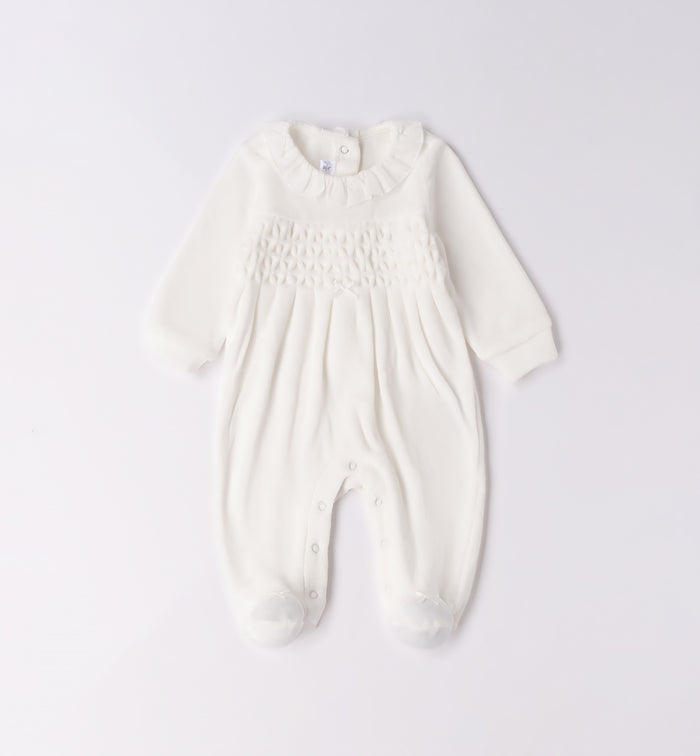 Tutina neonata in ciniglia bianco latte con ricamo nido d’ape piegata.