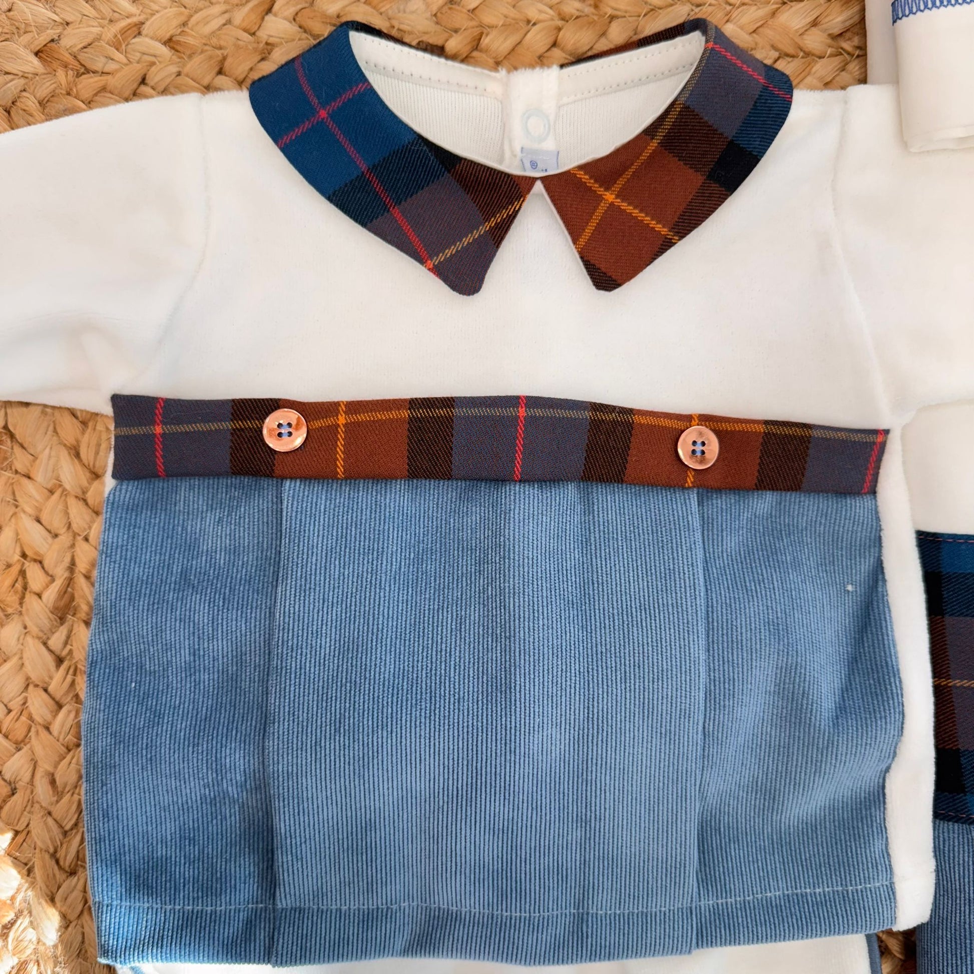 Dettaglio tutina neonato in ciniglia panna con inserto tartan e vellutino azzurro