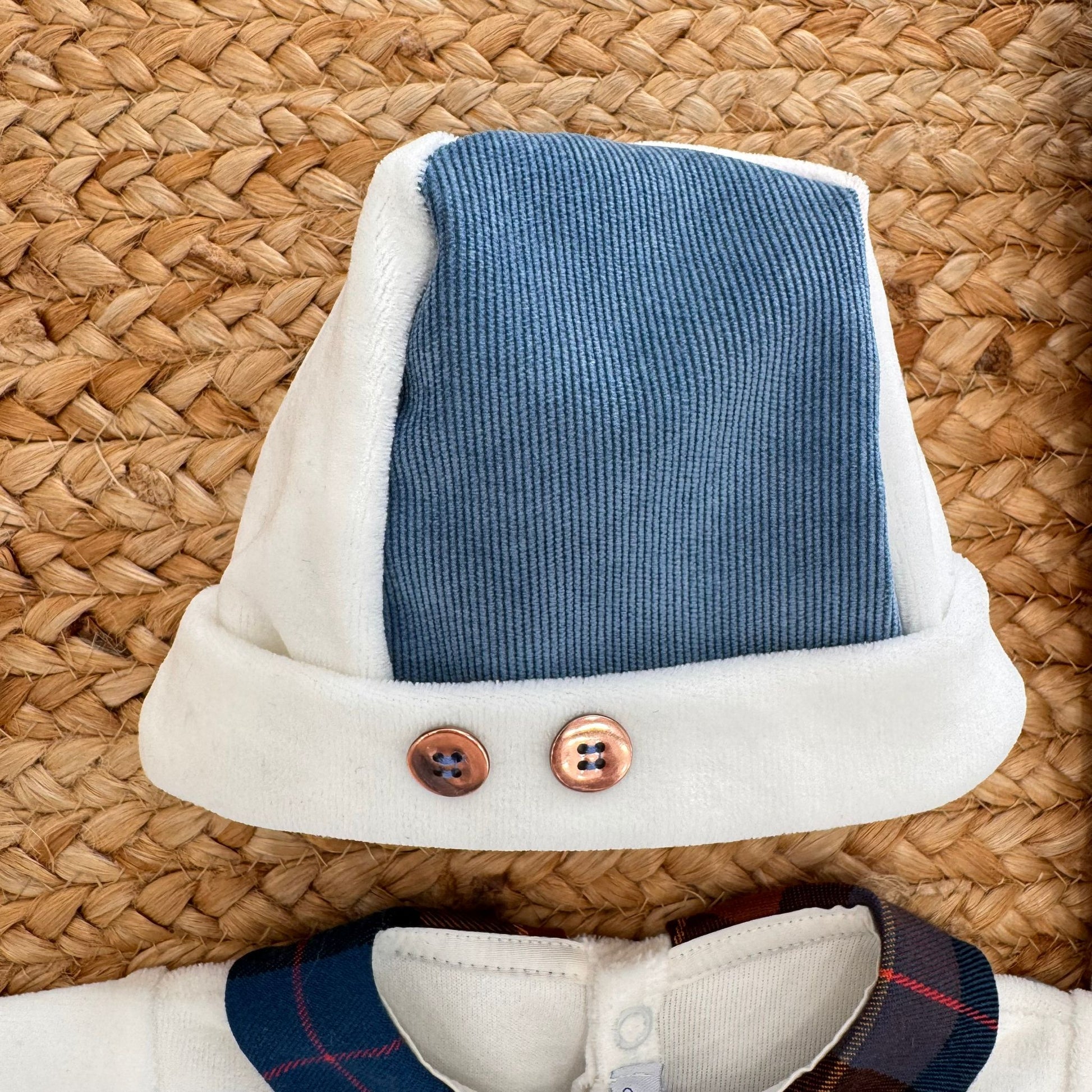 Dettaglio tutina neonato in ciniglia panna con inserto tartan e vellutino azzurro