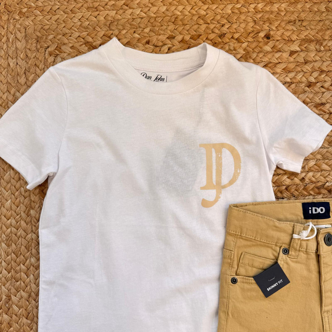 Outfit bambino con t-shirt bianca logo e pantalone senape skinny fit.