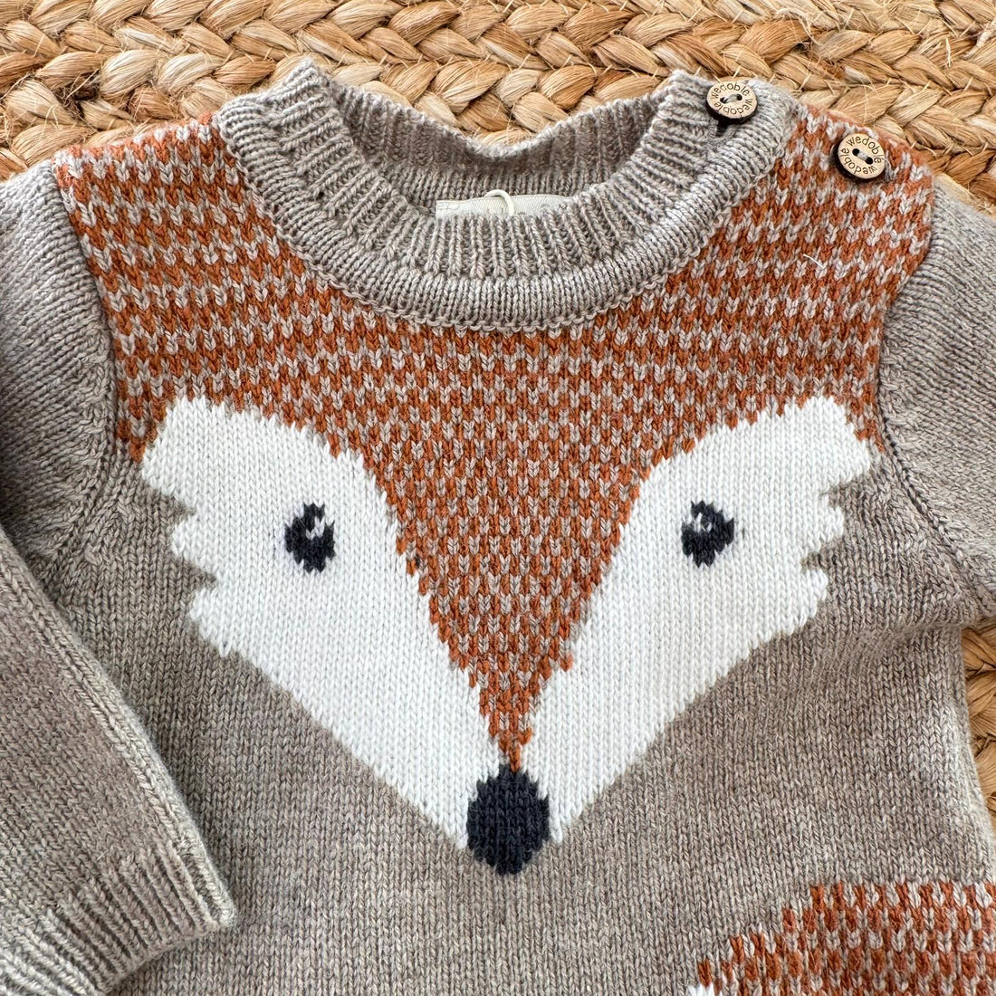 Tutina neonato in cashmere con volpe intarsiata, bottoni in legno e apertura sul cavallo. Calda e raffinata per l’inverno.