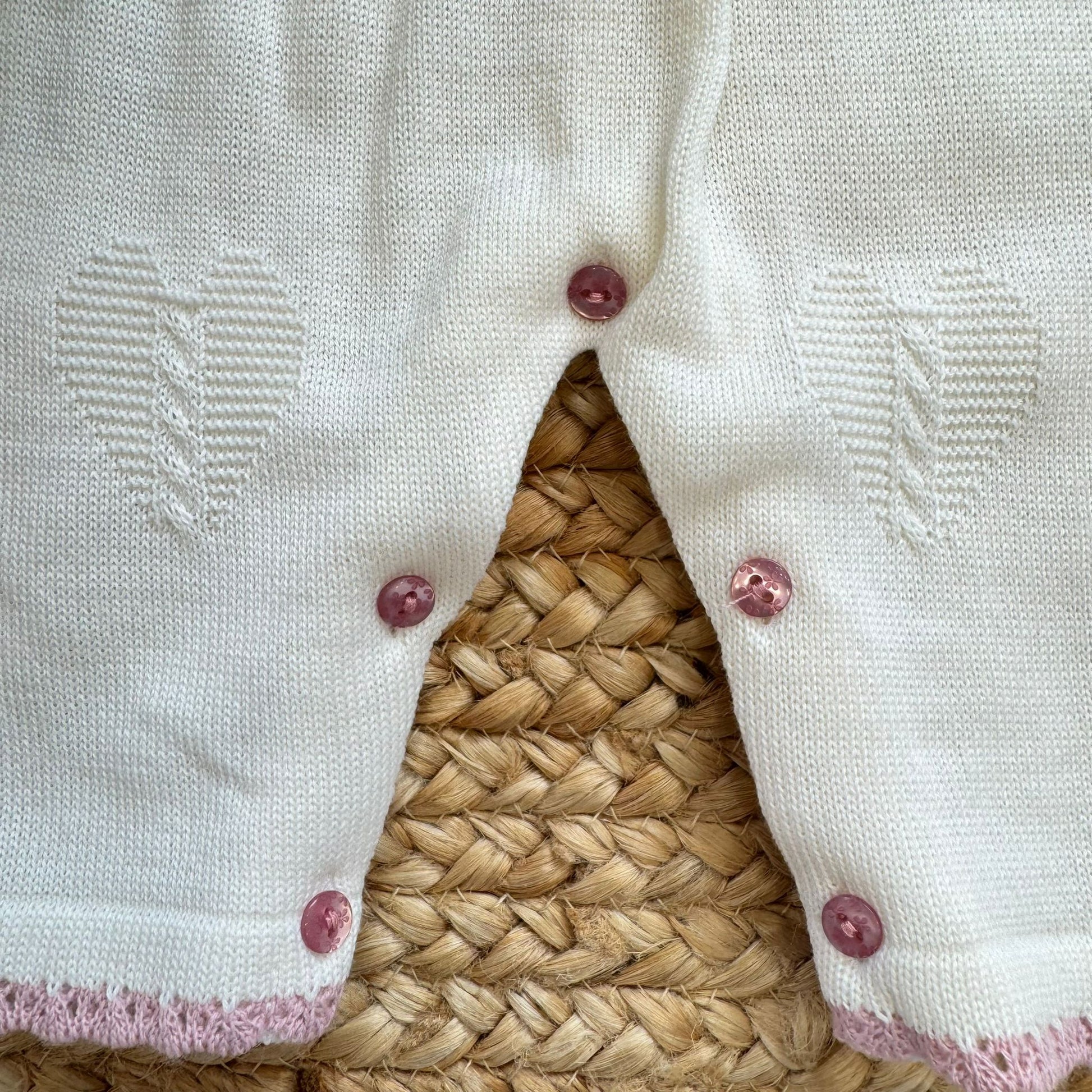 Bottoncini rosa sul fondo della tutina neonata panna e rosa