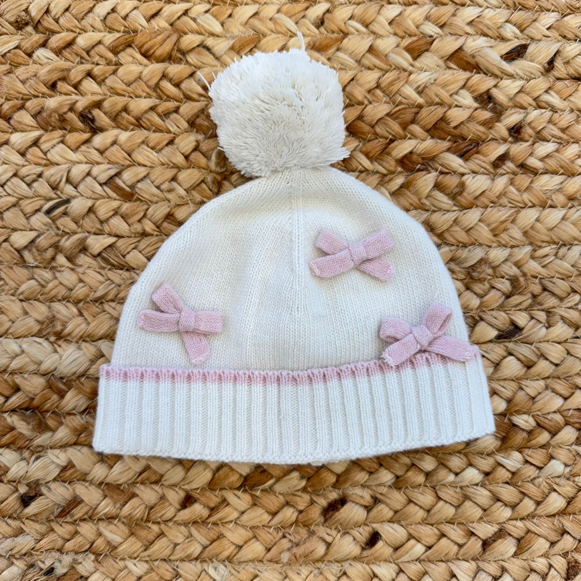 Cappellino neonata in lana panna con fiocchi rosa e pon pon