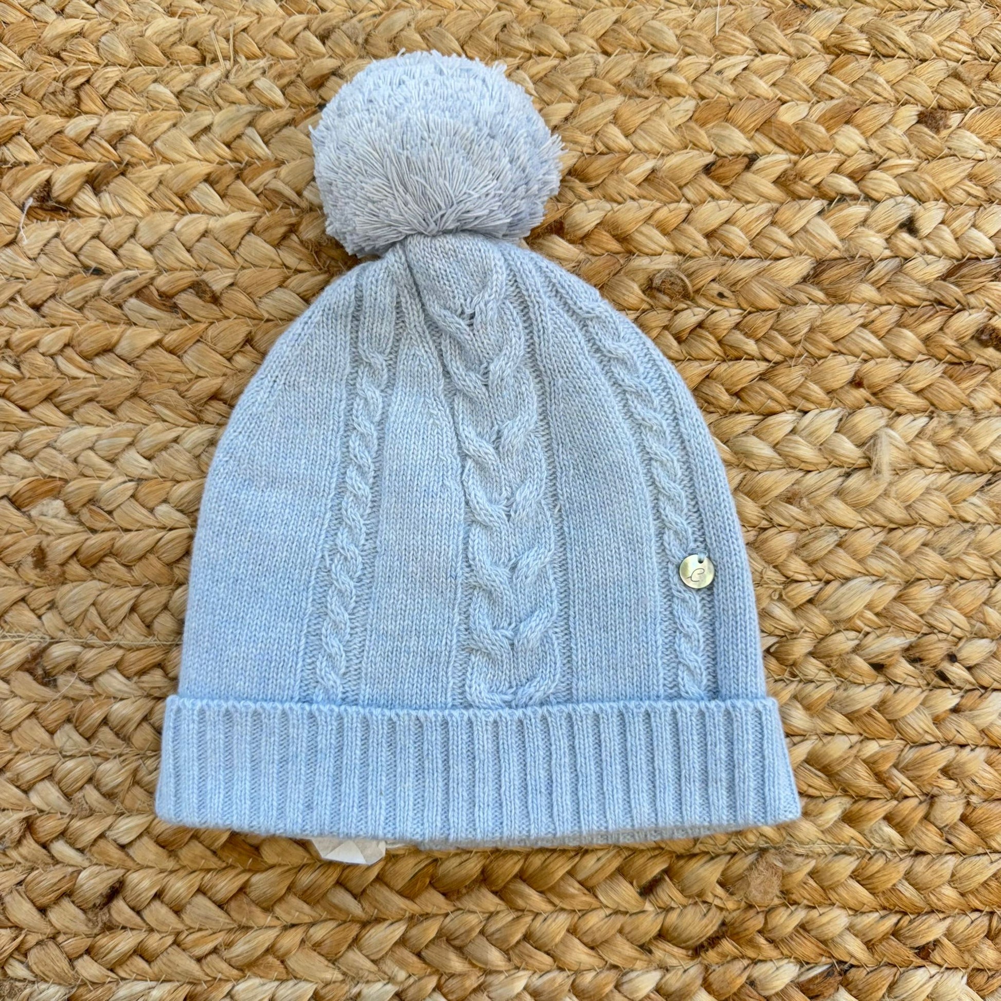Cappellino neonato azzurro in lana e cashmere con lavorazione a trecce e pon pon