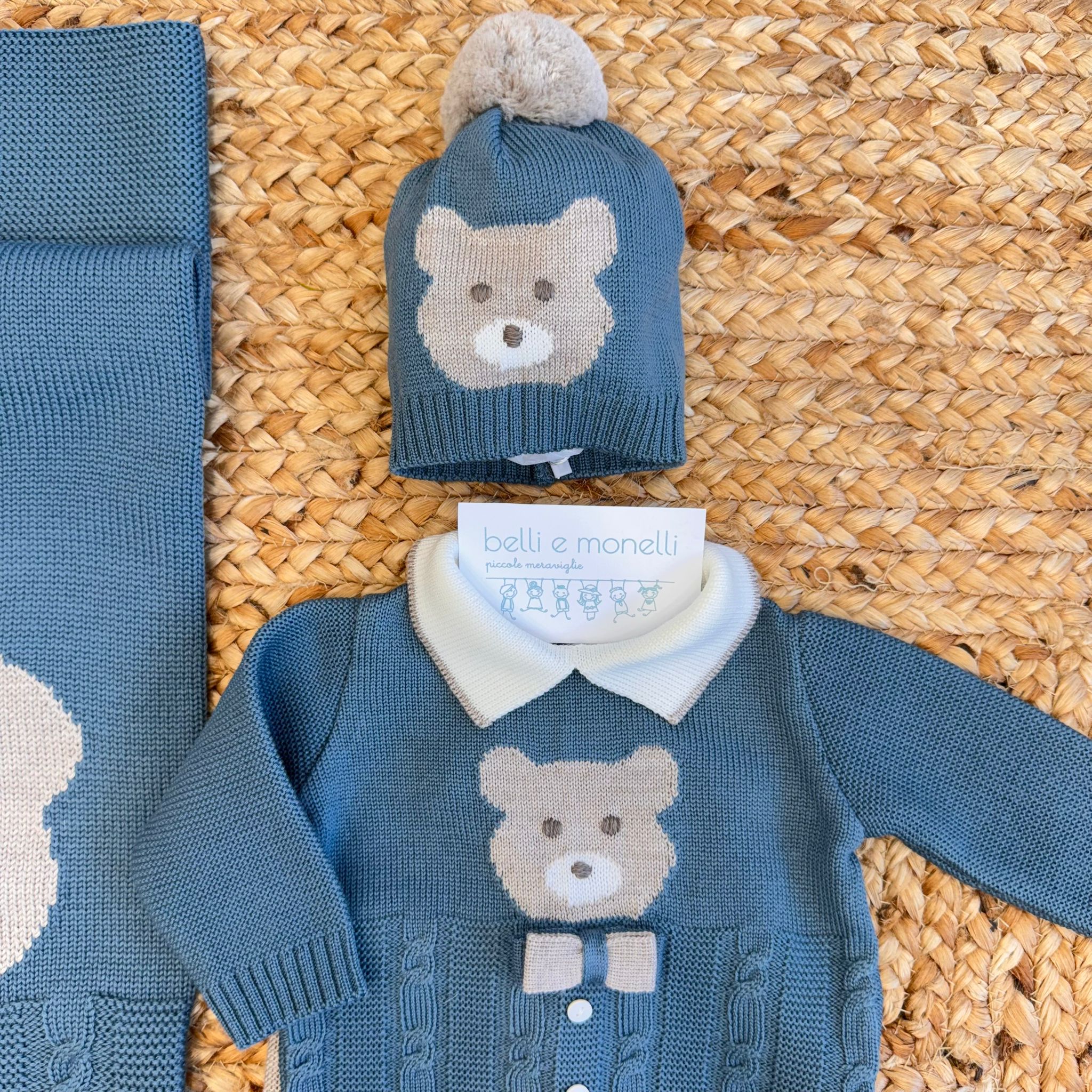 Coordinato neonato verde ottanio e sabbia in pura lana con orsetto ricamato, composto da tutina due pezzi, cappellino, scarpette e copertina.
