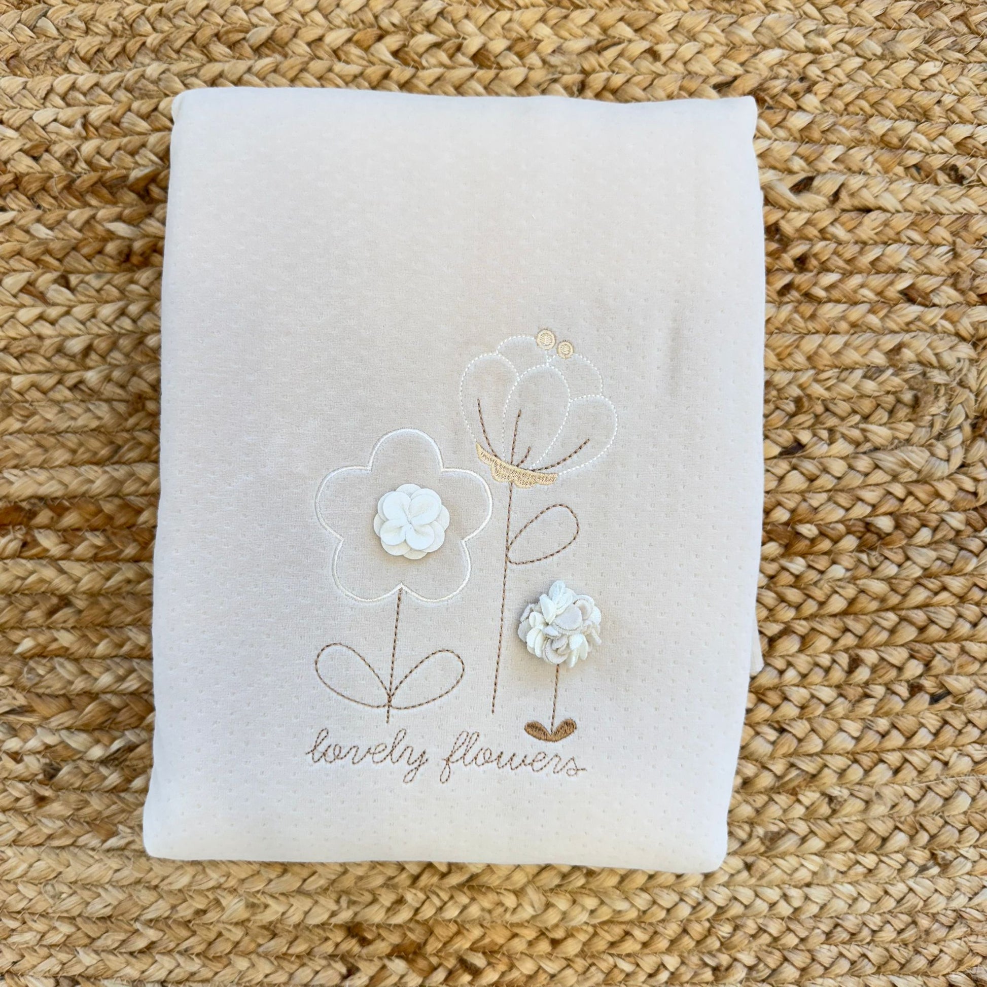 Copertina neonata beige con fiori ricamati piegata