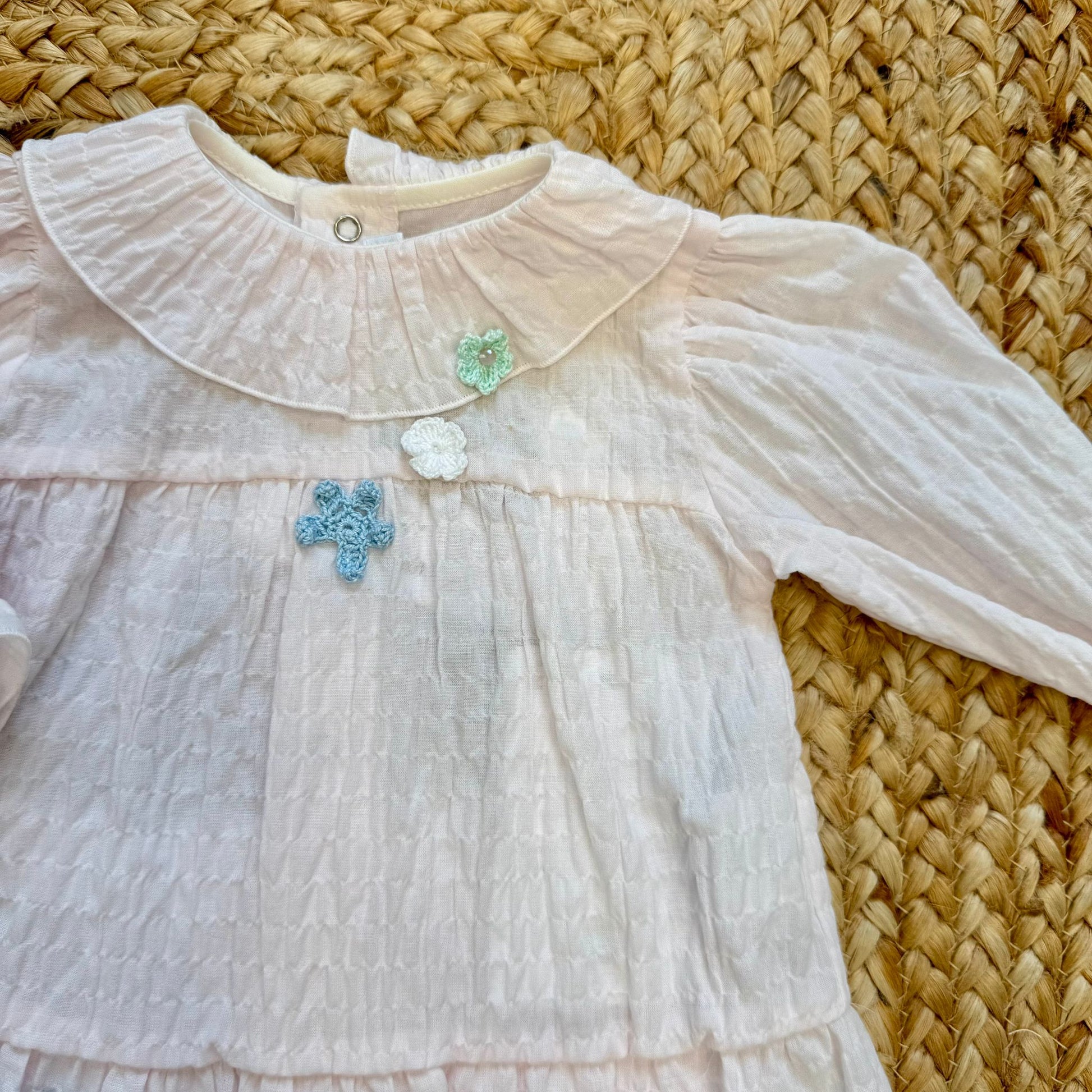 Dettaglio blusa per neonata con fiori applicati e colletto arrotondato