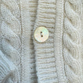 Dettaglio bottone madreperla su cardigan panna
