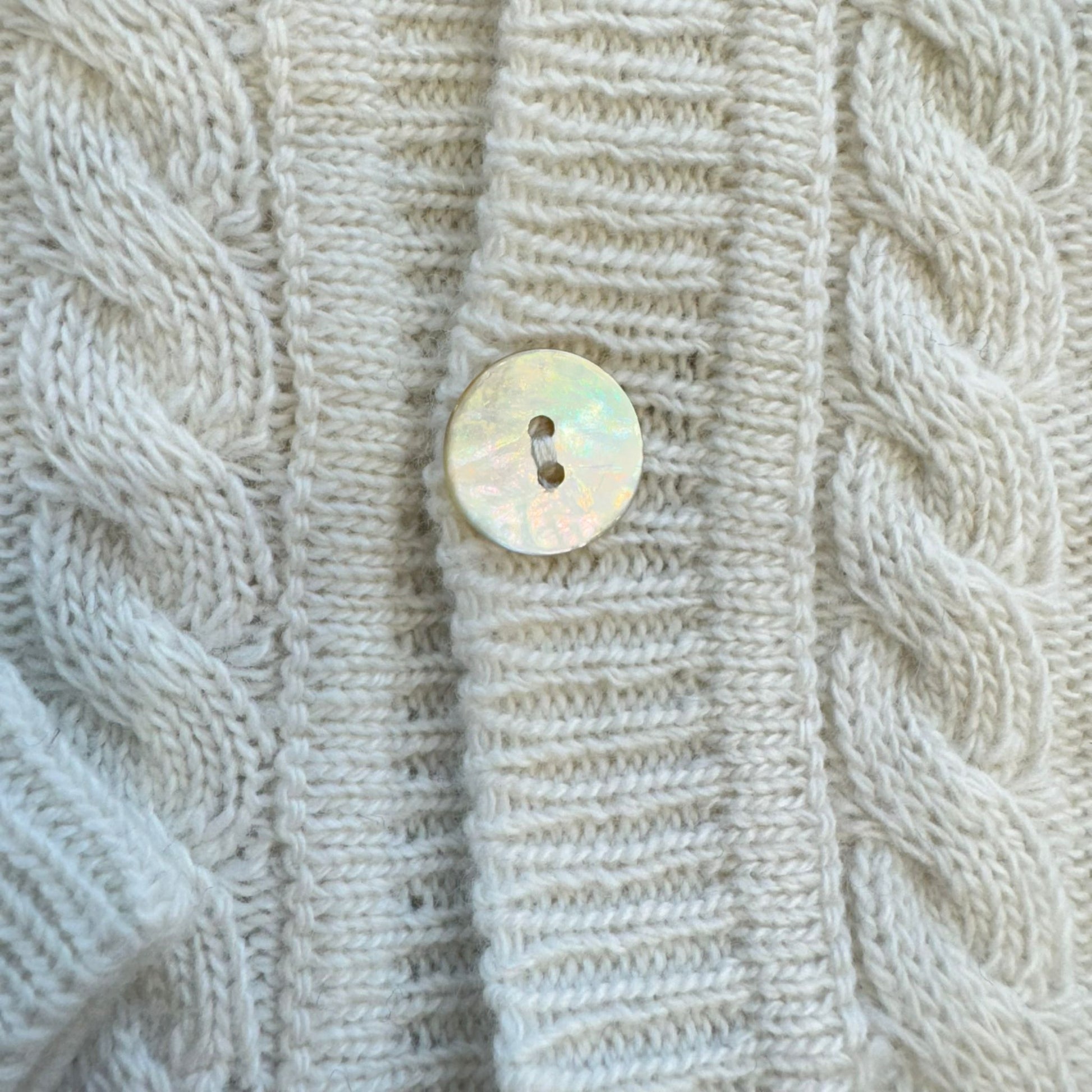 Dettaglio bottone madreperla su cardigan panna