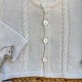 Dettaglio centrale bottoni madreperla su cardigan panna