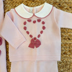 Dettaglio colletto bianco con bordo rosa e lavorazione a passanastro.