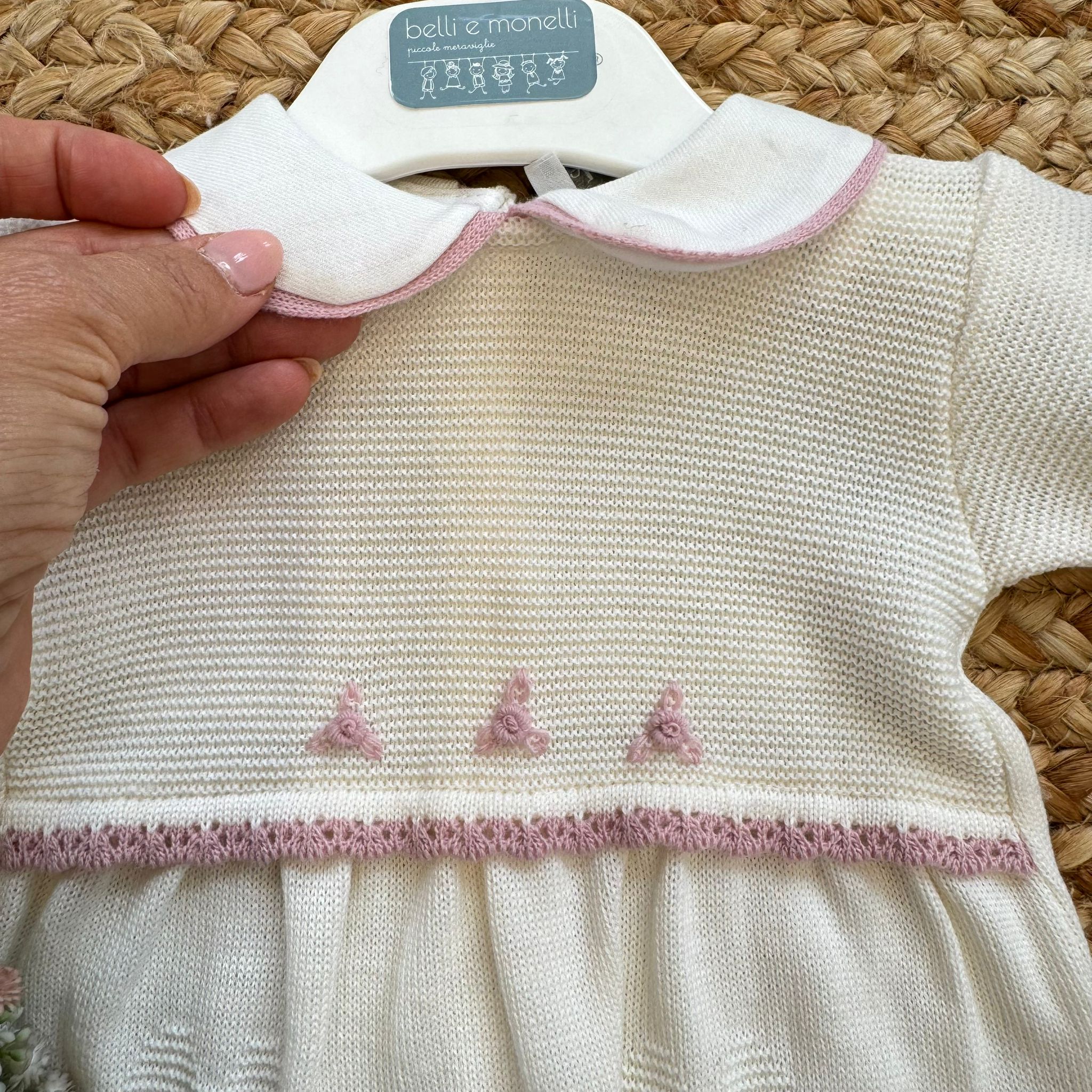 Dettaglio colletto bianco con profilo rosa della tutina neonata