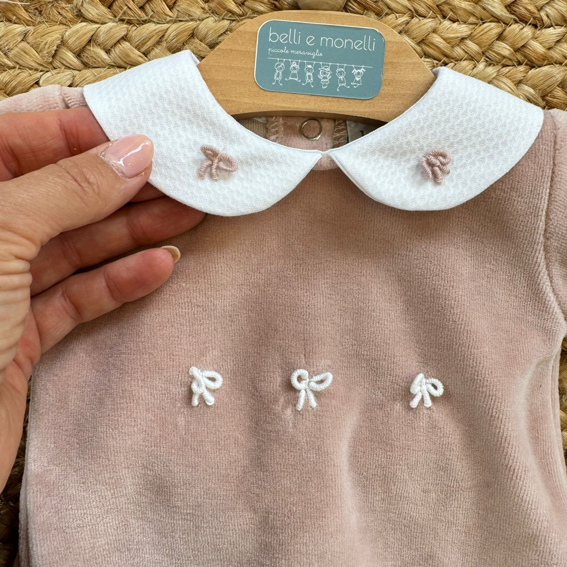 Dettaglio colletto bianco con ricami rosa cipria e fiocchetti sulla tutina in ciniglia