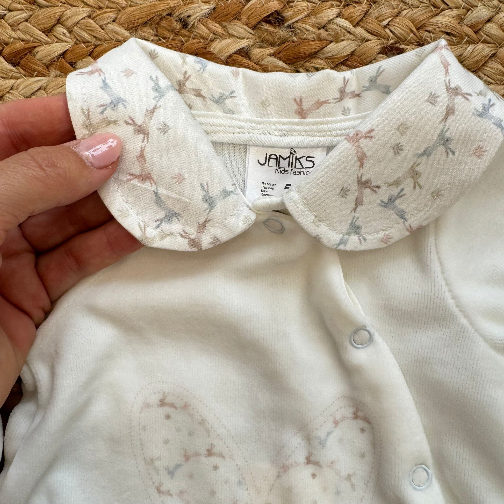Dettaglio colletto fantasia con coniglietti su tutina neonata bianca