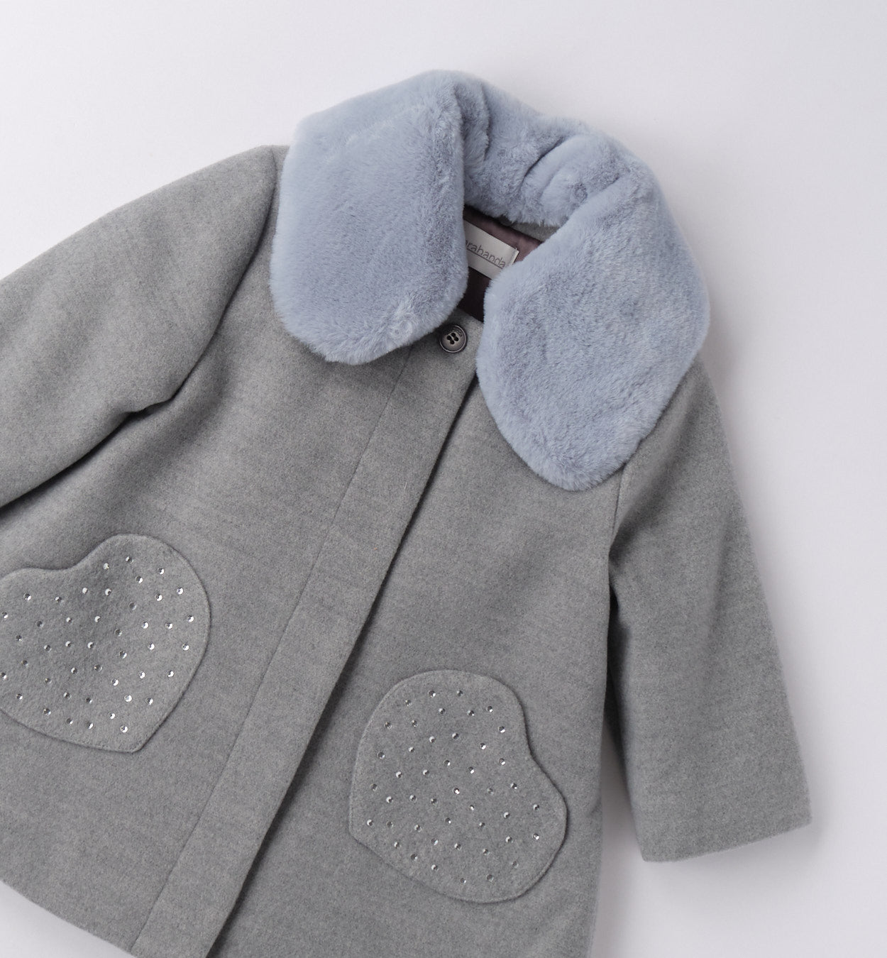 Dettaglio collo in pelliccia e tasche a cuore con strass