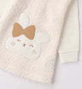 Dettaglio coniglio e fiocco beige su abito bimba panna
