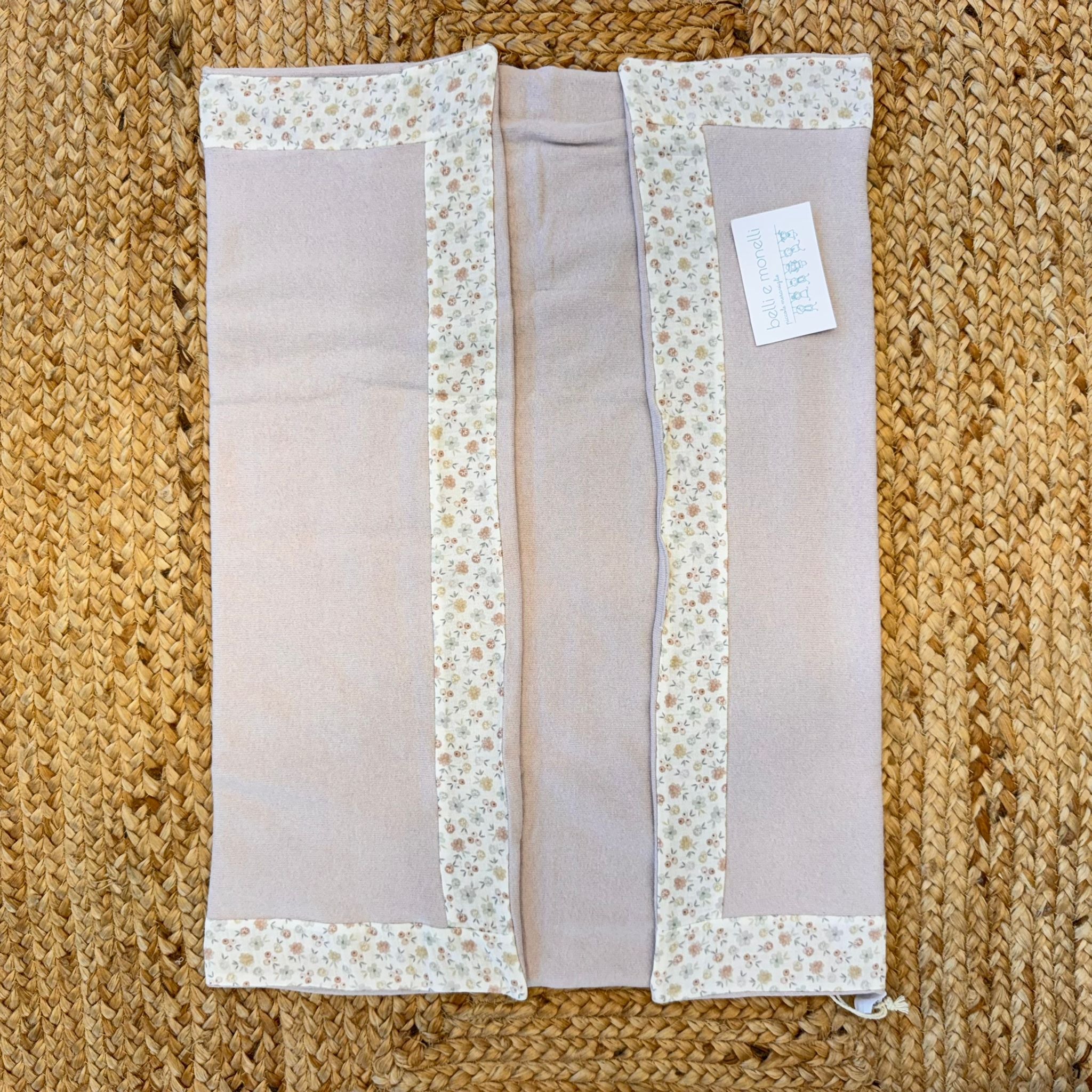 Dettaglio coperta neonata rosa cipria con bordo floreale.