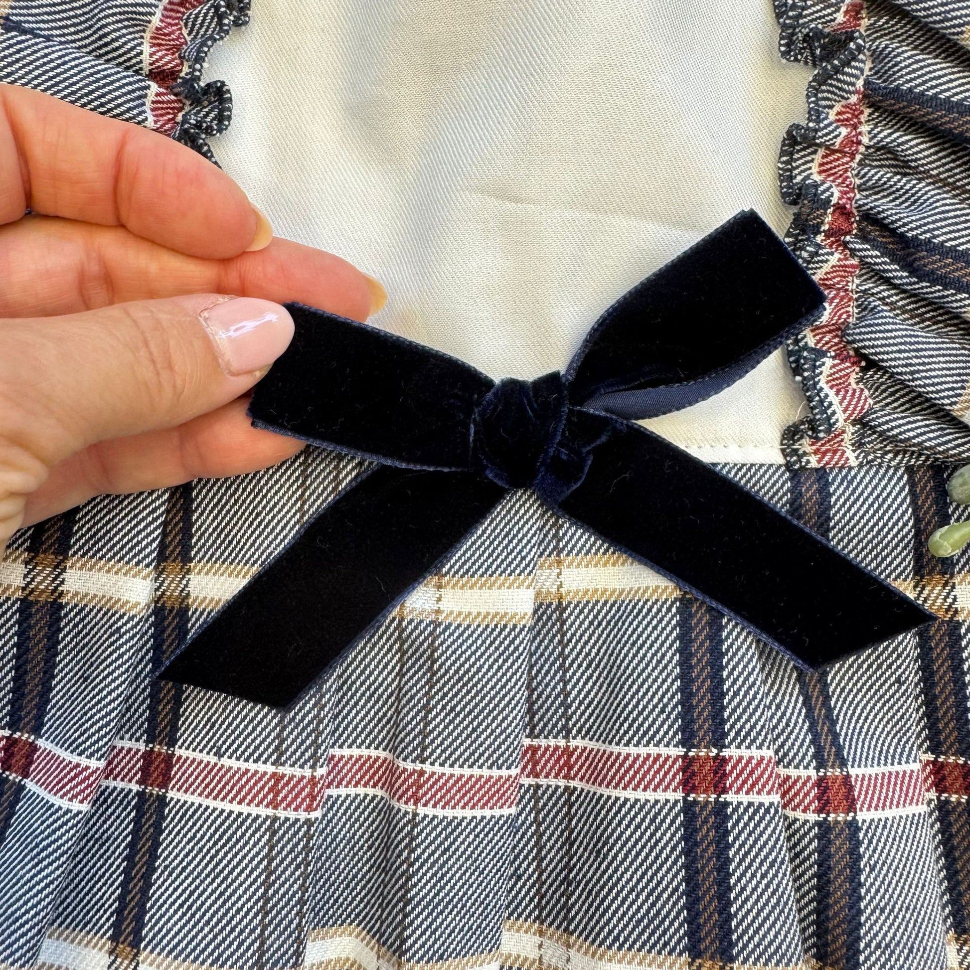 Dettaglio fiocco in velluto blu sul vestito neonata