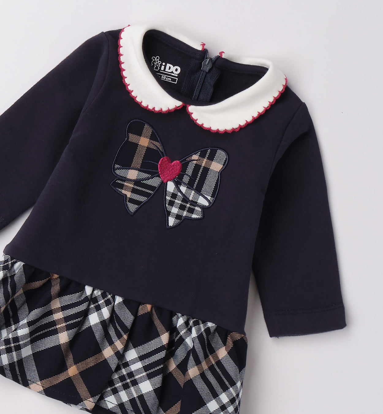 Dettaglio fiocco scozzese con cuore ricamato sul vestito neonata