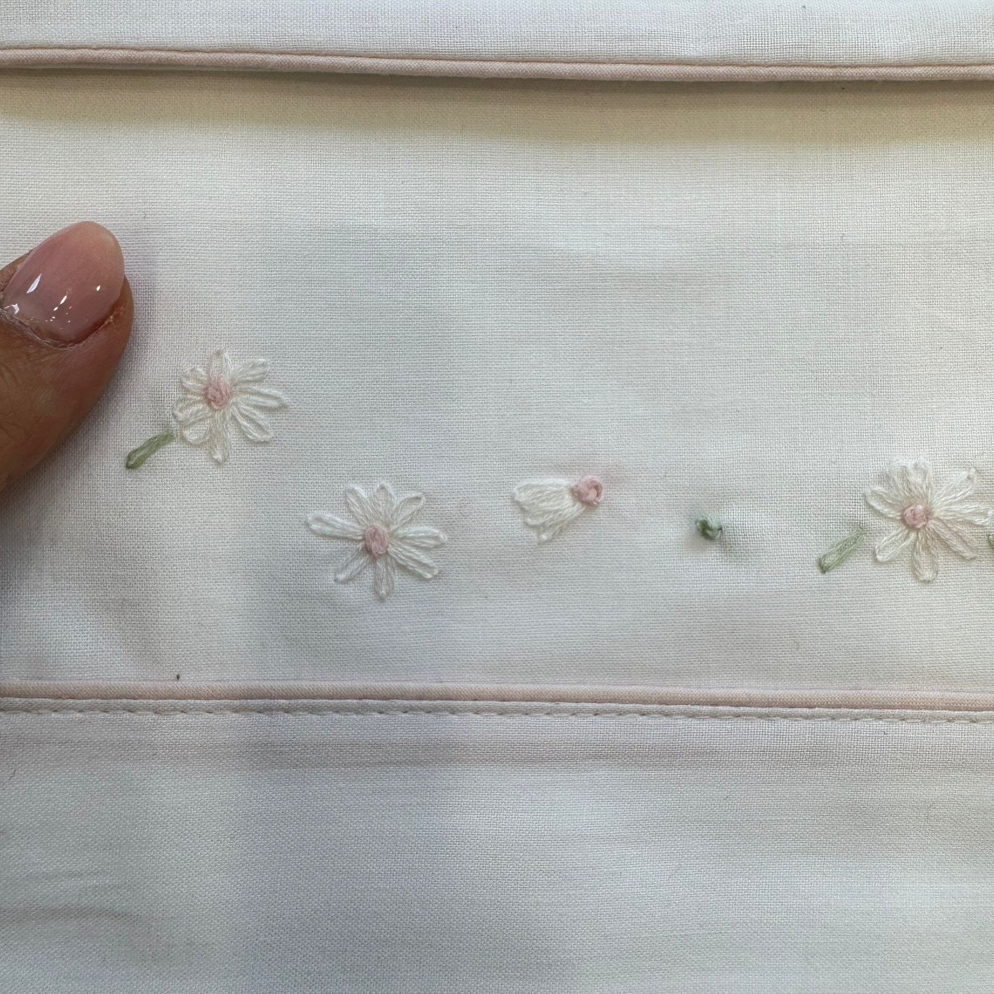 Dettaglio fiorellini ricamati a mano sul lenzuolo in cotone