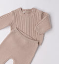 Dettaglio maglia a trecce e pantalone coordinato in cotone e lana.