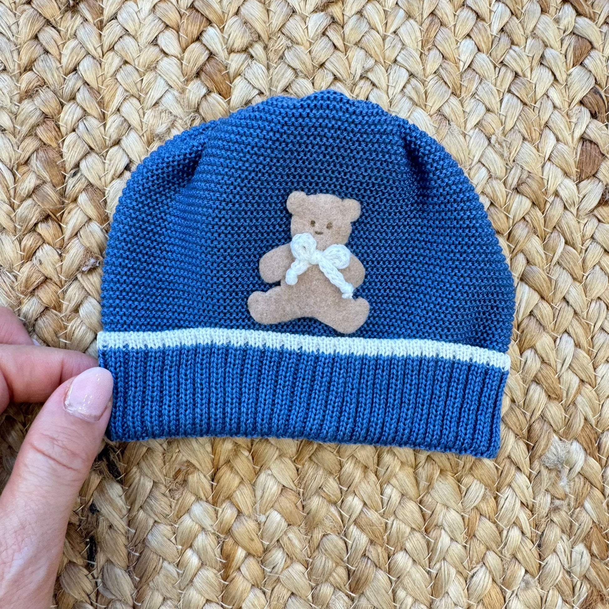 Dettaglio maglia pura lana blu con tasche e orsetto