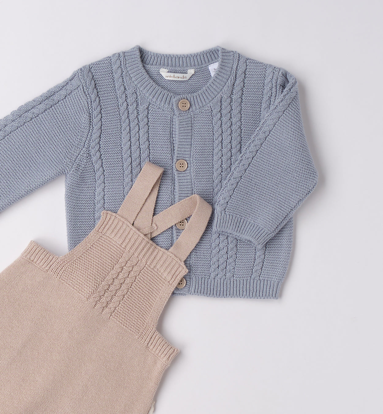 Dettaglio maglioncino azzurro e salopette beige in maglia