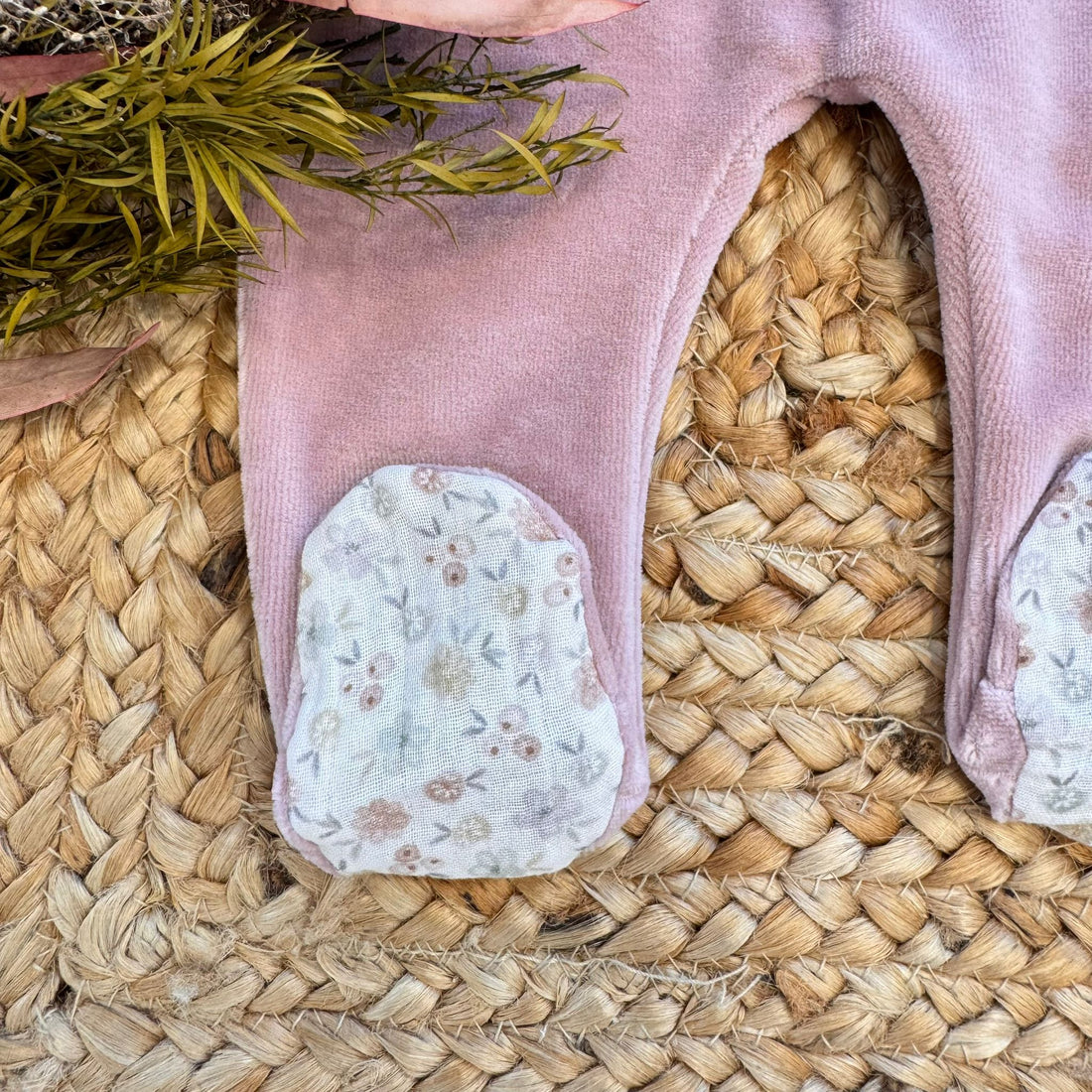 Tutina neonata in ciniglia rosa con ricami floreali e dettagli fantasia.