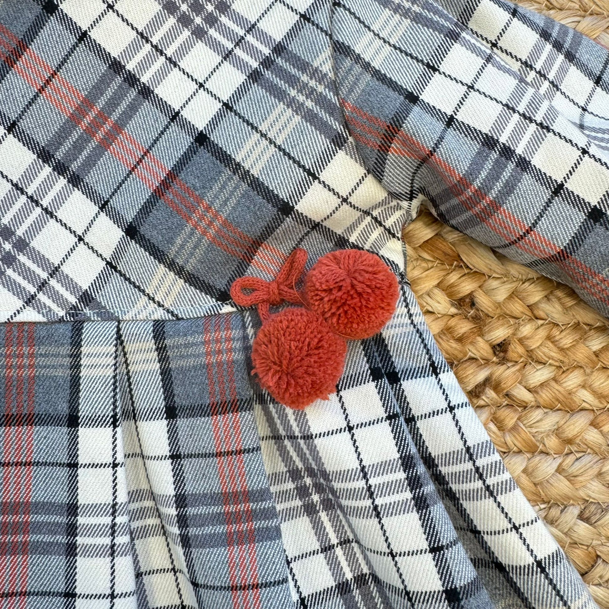 Dettaglio pompon rossi applicati in vita abito bambina
