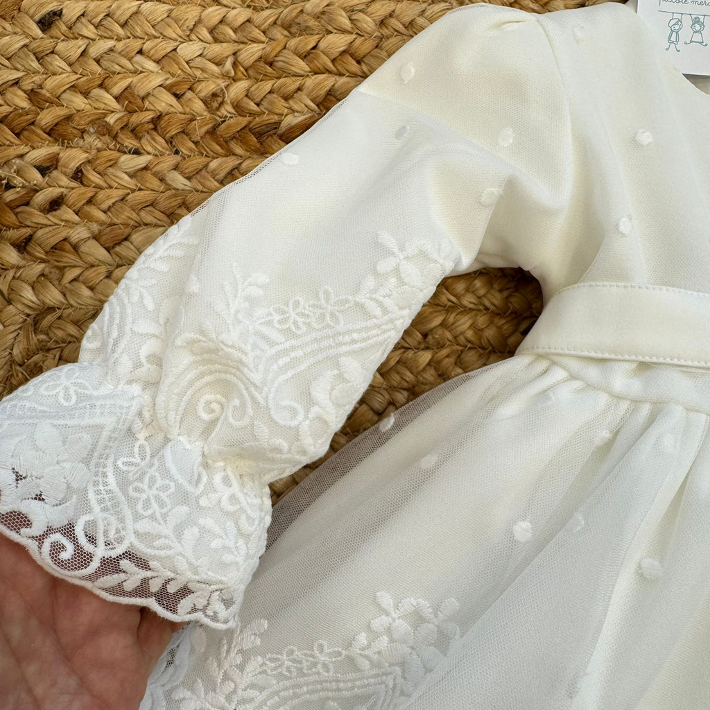 Dettaglio pon pon bianco abito battesimo neonata elegante