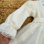 Dettaglio pon pon bianco abito battesimo neonata elegante