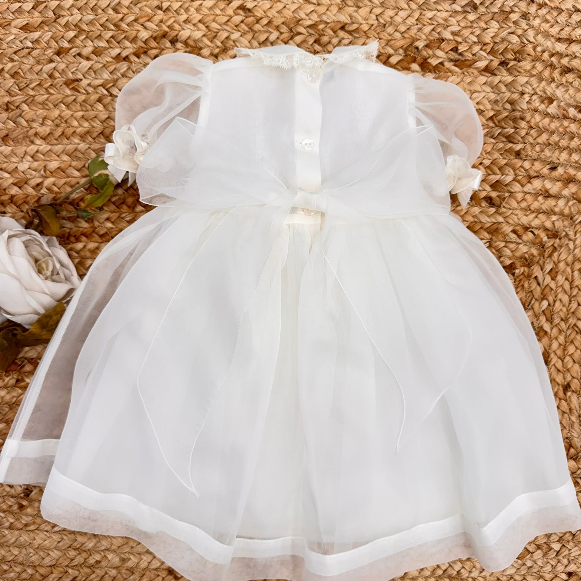 Dettaglio ricami artigianali floreali su abito battesimo bimba elegante