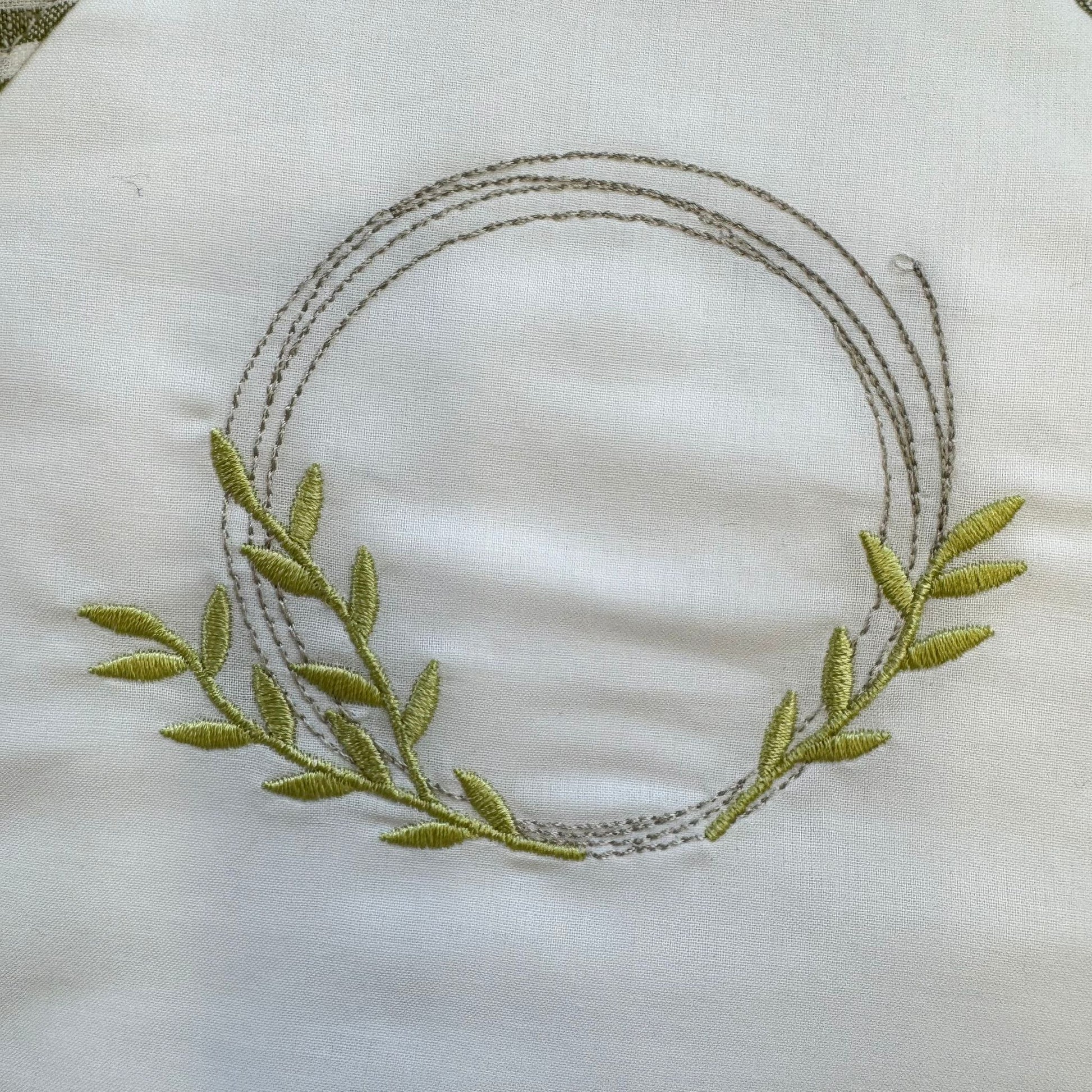 Dettaglio ricamo corona verde accappatoio neonato