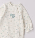 Dettaglio ricamo cuori rosa e beige su tutina neonata in caldo cotone panna.