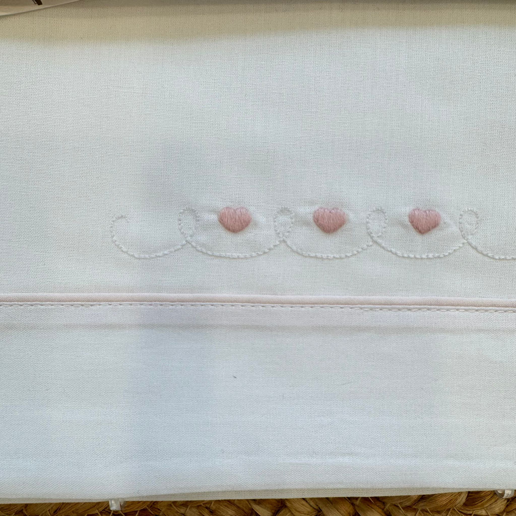 Dettaglio ricamo cuori rosa sul lenzuolo neonata