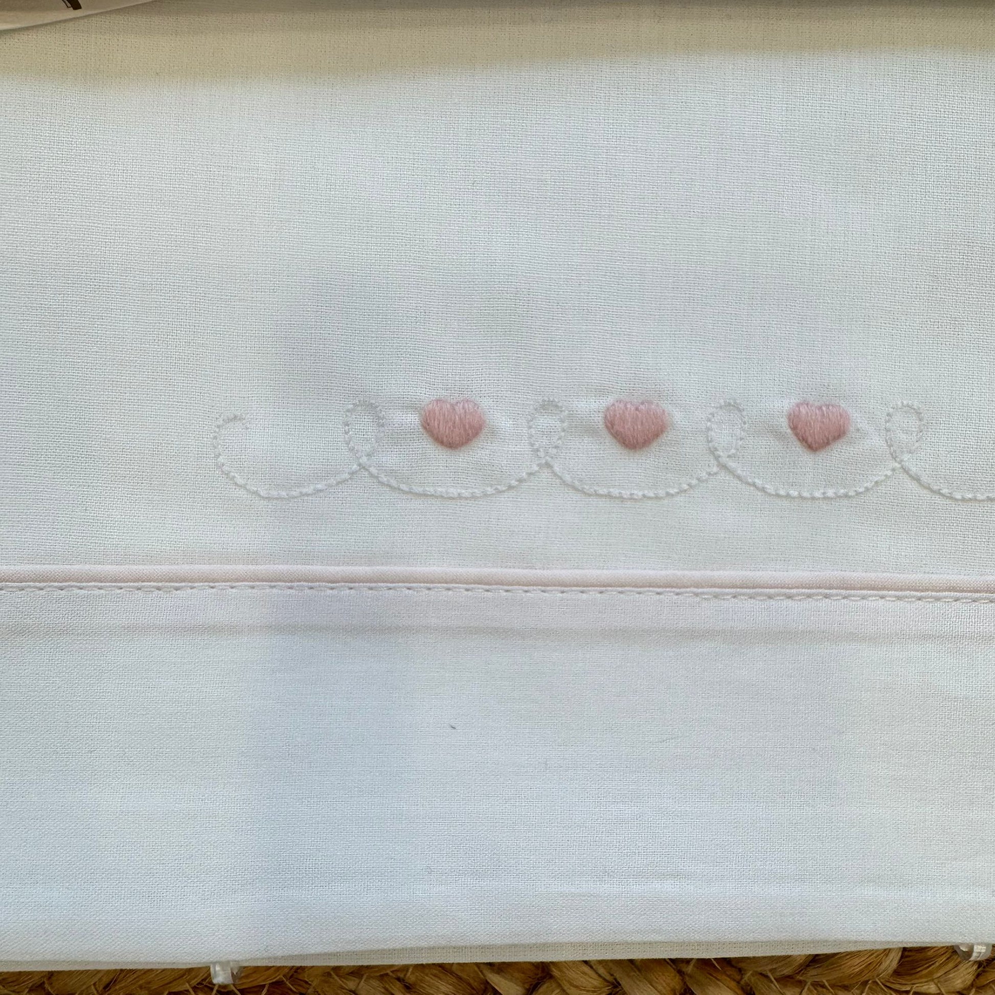 Dettaglio ricamo cuori rosa sul lenzuolo neonata