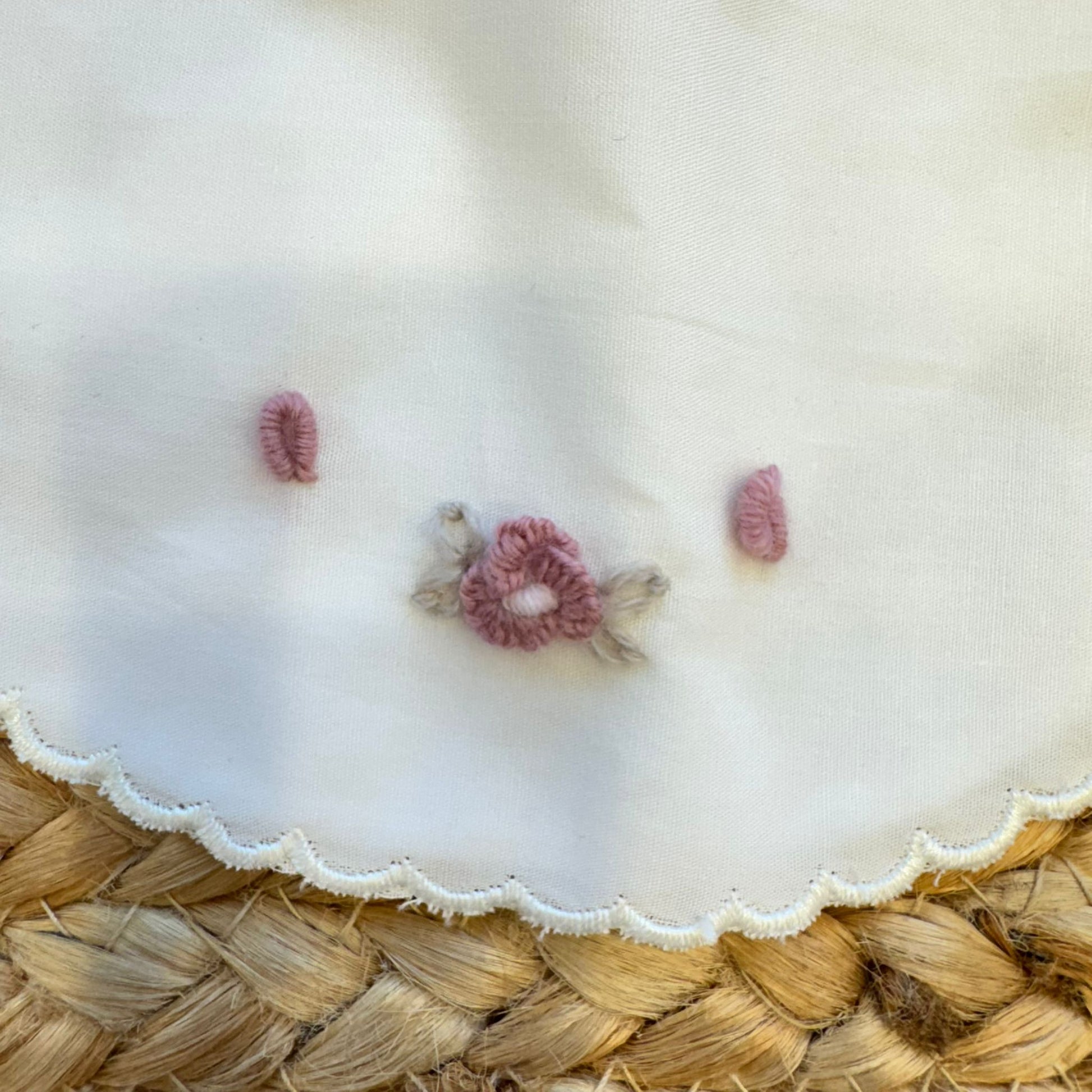 Dettaglio ricamo floreale a mano su bavetta neonata in cotone