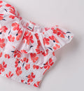 Dettaglio del tessuto con stampa floreale corallo e rifinitura volant del top bambina.