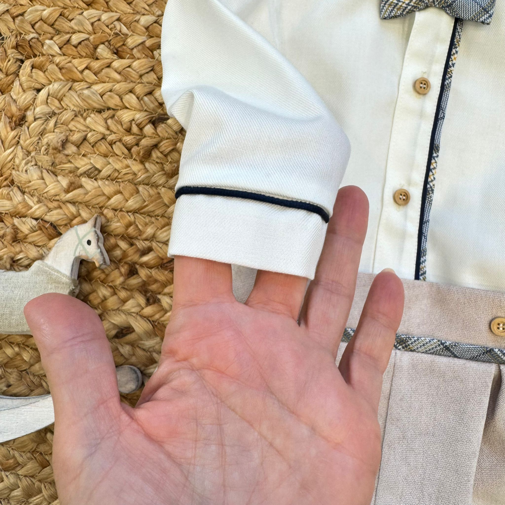 Dettaglio polsino camicia panna con profilo blu