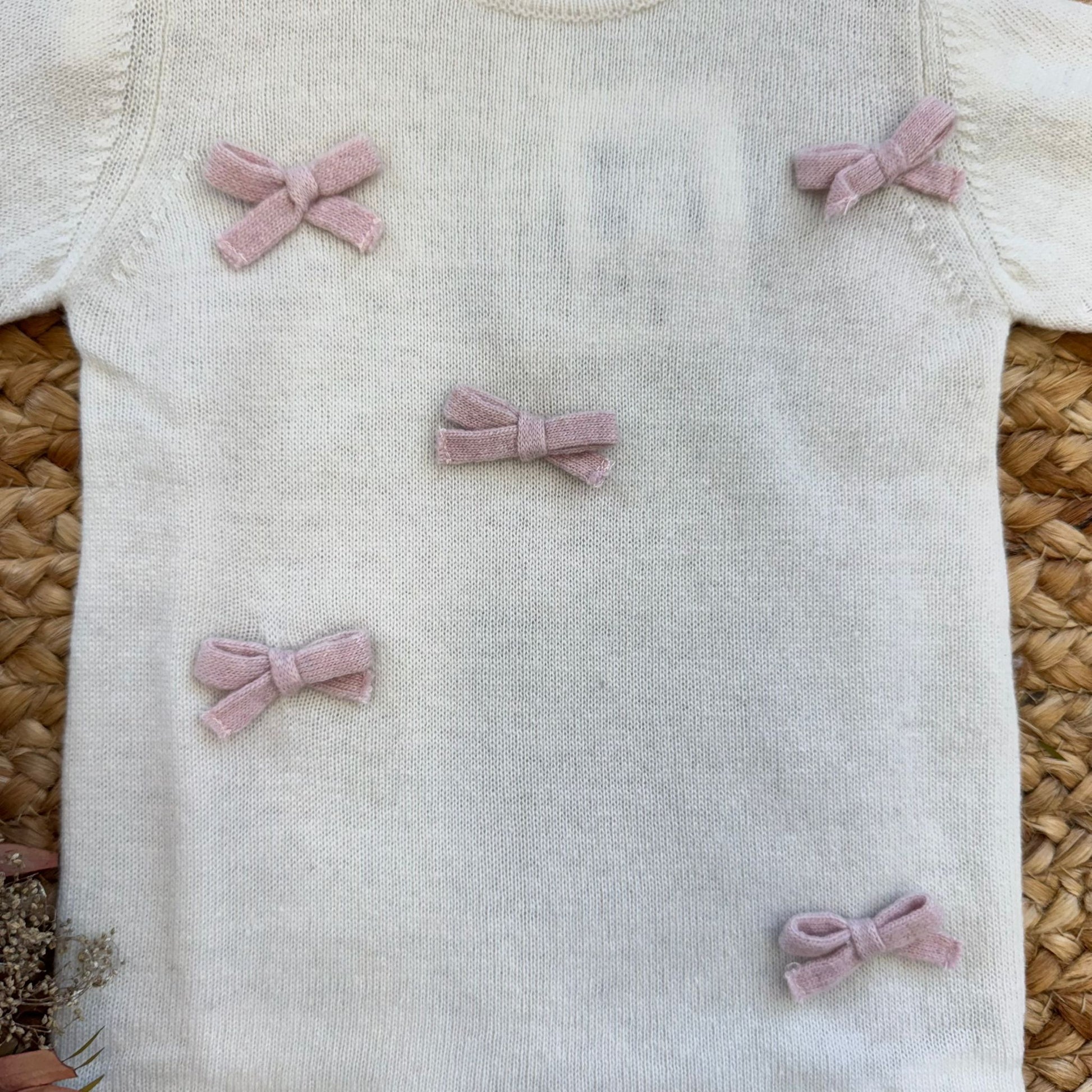 Fiocchi rosa applicati su tutina panna in maglia pregiata