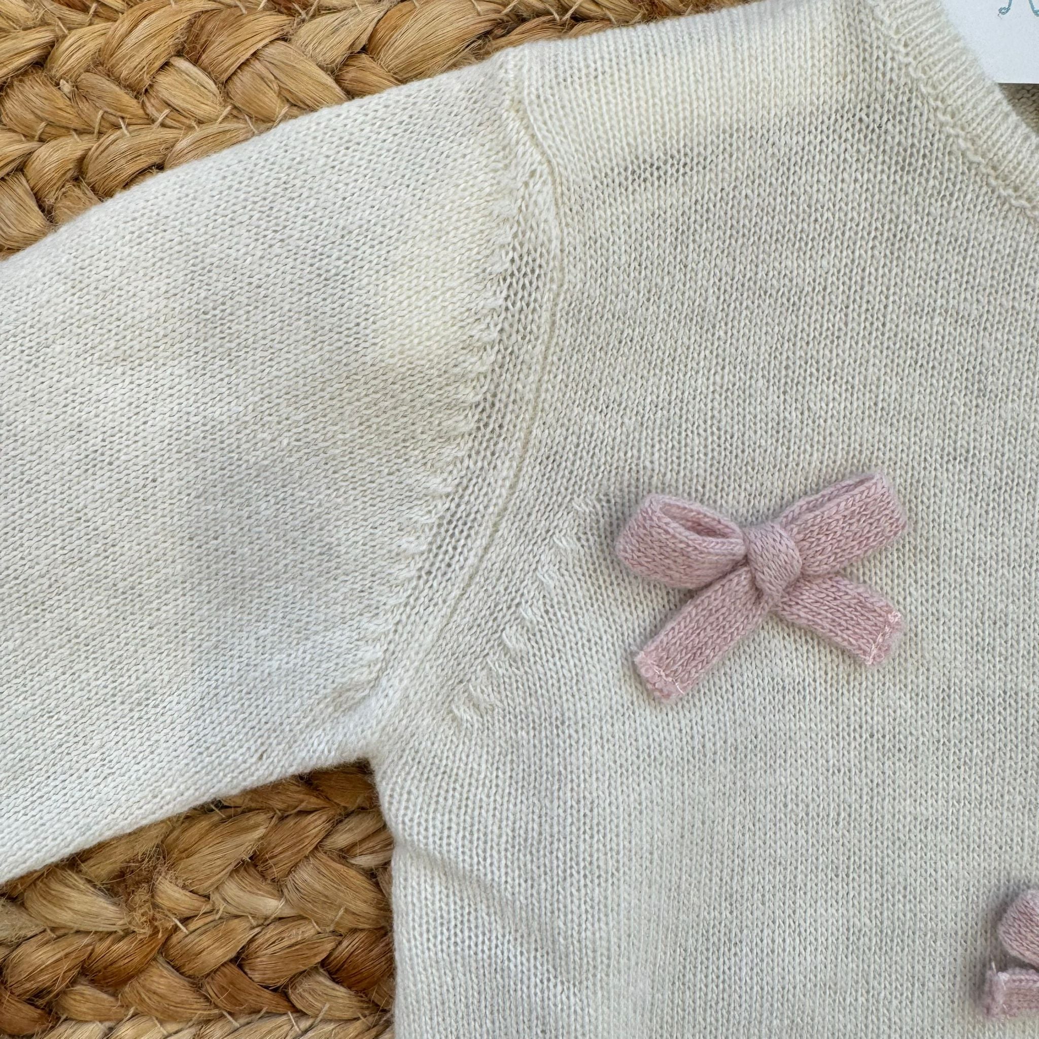 Manica e dettaglio fiocco rosa su tutina in maglia panna