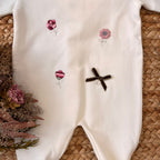 Ricami a fiorellini rosa e rossi con fiocco in velluto e charm applicato.